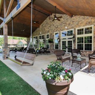 A beautiful outdoor patio with a swing and comfortable seating area under a covered roof.