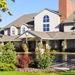 Front view of a charming residential building surrounded by landscaped gardens and a clear blue sky.