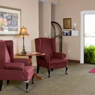 A cozy hotel lobby with two red armchairs, a lamp, and a small table.