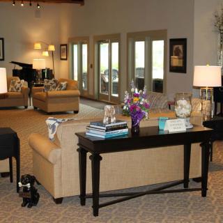 A spacious living room with a cozy sofa, elegant lamps, and a piano in the background.