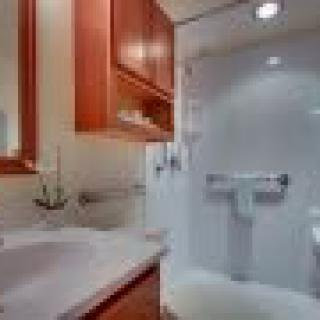 A small bathroom featuring a shower, sink, and wooden cabinets.