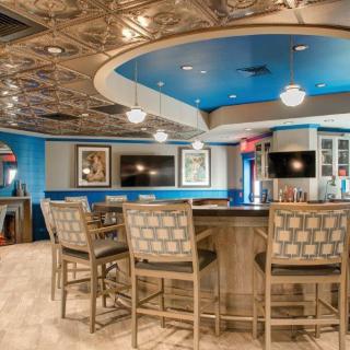 A modern bar with stylish seating and decorative ceiling tiles.