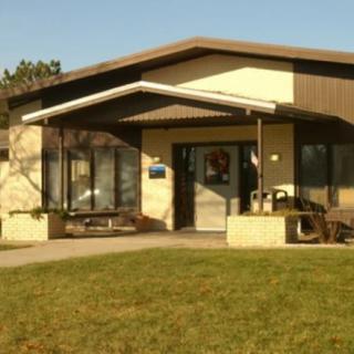 A small building with a prominent entrance and large glass windows on a sunny day.