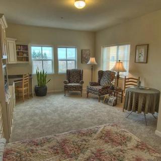 A cozy living room with comfortable seating, large windows, and warm lighting.