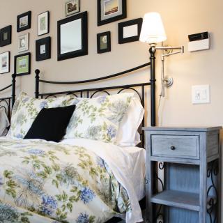 A cozy bedroom with floral bedding and a gallery wall above the bed.