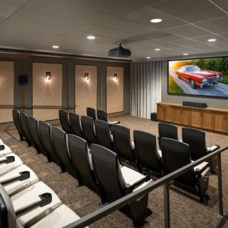An empty home theater with rows of comfortable seating and a large screen displaying an image.