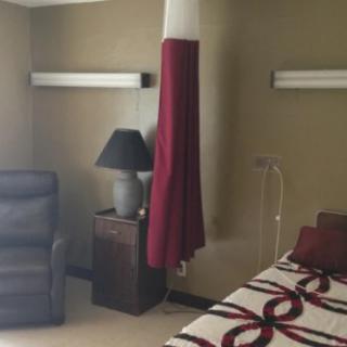 A hospital room with a bed, chair, lamp, and privacy curtain.