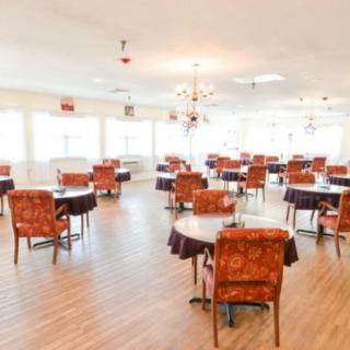 An empty dining area with tables and chairs arranged on a wooden floor.