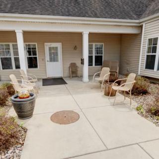 A cozy outdoor patio area with chairs and plants at the entrance of a building.
