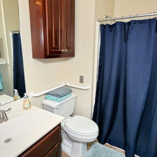 A clean bathroom featuring a sink, toilet, and blue shower curtain.