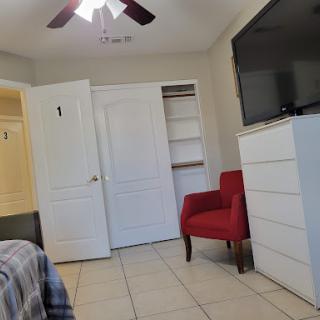 A cozy bedroom featuring a red chair, ample storage space with closets, and a mounted television.