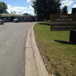 View of the building with a sign for the health and rehabilitation center along a paved road.