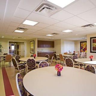 A spacious dining room with round tables and floral centerpieces.