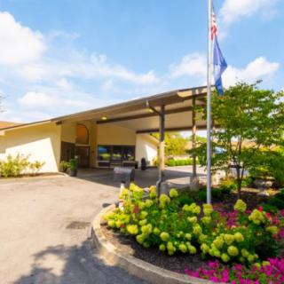 A building entrance with colorful landscaping and flags flying.