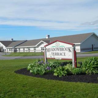 A landscaped view of a retirement home with a sign reading 'Meadowbrook Terrace'.