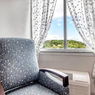 A cozy chair by the window with patterned curtains, offering a scenic view outside.