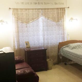 A cozy bedroom featuring soft curtains, a comfortable bed, and warm lighting.
