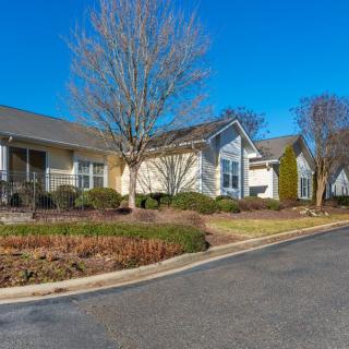 A suburban residential house with a well-maintained landscape and clear blue sky.