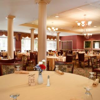 An elegant dining room with neatly arranged tables and chairs, set for a meal.