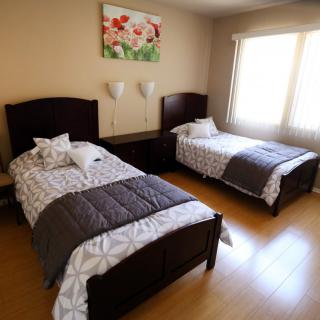 A cozy bedroom with two twin beds and a large window letting in natural light.