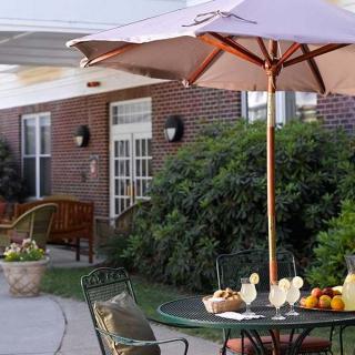 A cozy outdoor patio with a table and umbrella set in front of a brick building.