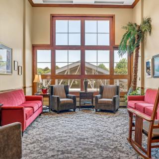 A cozy lobby seating area with red sofas, armchairs, and a large window providing natural light.
