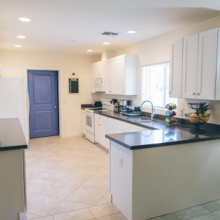 A modern kitchen with sleek countertops, white cabinets, and stainless steel appliances.