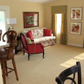 A cozy living room with a floral sofa, armchair, and decorative artwork on the walls.