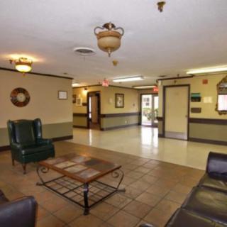 A hotel lobby with seating and a coffee table, featuring tiled floors and decorative lighting.