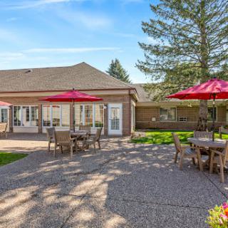 A sunny outdoor patio with dining tables and red umbrellas, perfect for enjoying a meal in the garden.