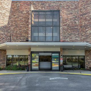 The image shows a modern building entrance with a brick facade and large glass windows.