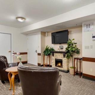A cozy living room with armchairs, a fireplace, and a wall-mounted television.