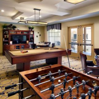 A cozy game room featuring a pool table and foosball table, complete with a television and comfortable seating.
