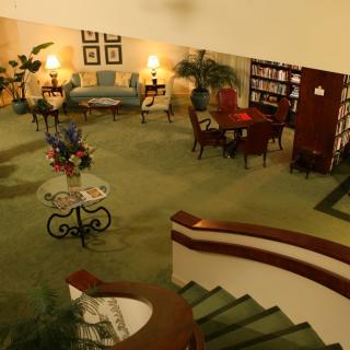 A cozy lobby with seating area, library shelves, and a spiral staircase.