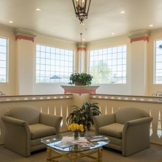 A cozy lounge area with two sofas, a glass coffee table, and large windows providing natural light.