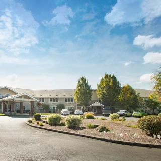 A large building with a surrounding parking lot and well-maintained landscaping on a clear day.