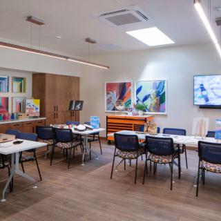 A spacious art studio with tables, chairs, and various art supplies.