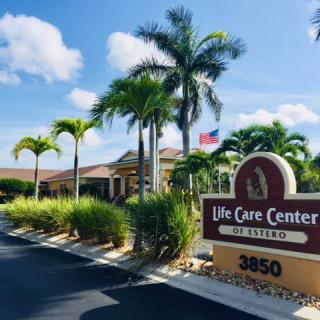 Exterior view of the Life Care Center with palm trees and a welcoming entrance sign.