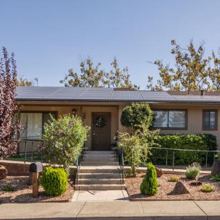 A well-maintained single-story house with a landscaped front yard featuring shrubs and trees.