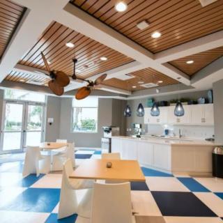 A modern kitchen interior with wooden ceilings, checkered flooring, and ample lighting.