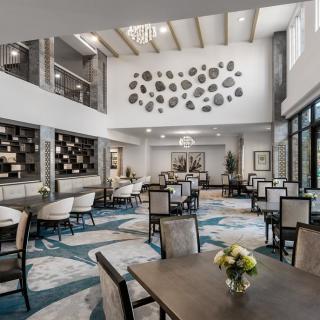 A modern dining area with elegant furniture, high ceilings, and contemporary artwork.