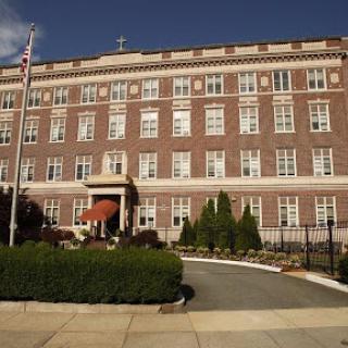 A well-maintained brick building featuring numerous windows and a landscaped entrance.