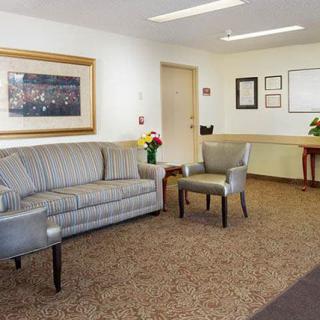 A cozy waiting room with a sofa, chairs, and a small table, decorated with flowers and artwork on the walls.