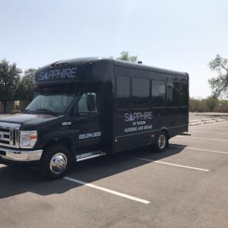 A shuttle bus parked in an empty parking lot on a sunny day.