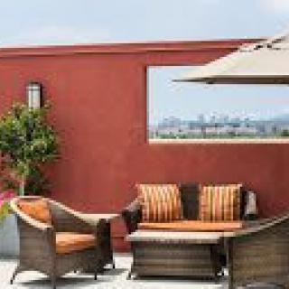 A cozy outdoor patio with wicker furniture and a large umbrella.