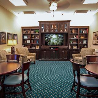 A cozy living room with bookshelves, comfortable seating, and a large television.