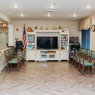 A well-organized waiting area featuring a television and an American flag, surrounded by arranged seating.