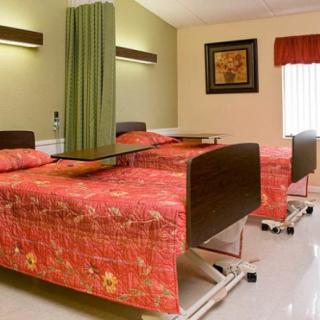 A hospital room with two beds, separated by a green privacy curtain and matching decor.
