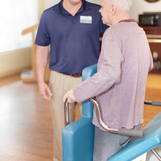 A caregiver assists an elderly person in a rehabilitation setting.
