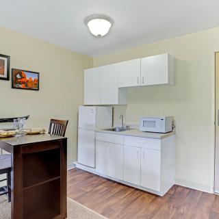 A minimalist apartment kitchen with white cabinets and a small dining area.